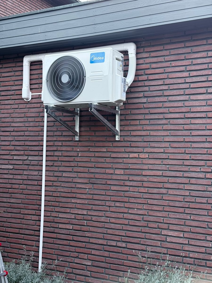 Außengerät auf Wandkonsole an einer Klinkerfassade, Leitungen im Kabelkanal